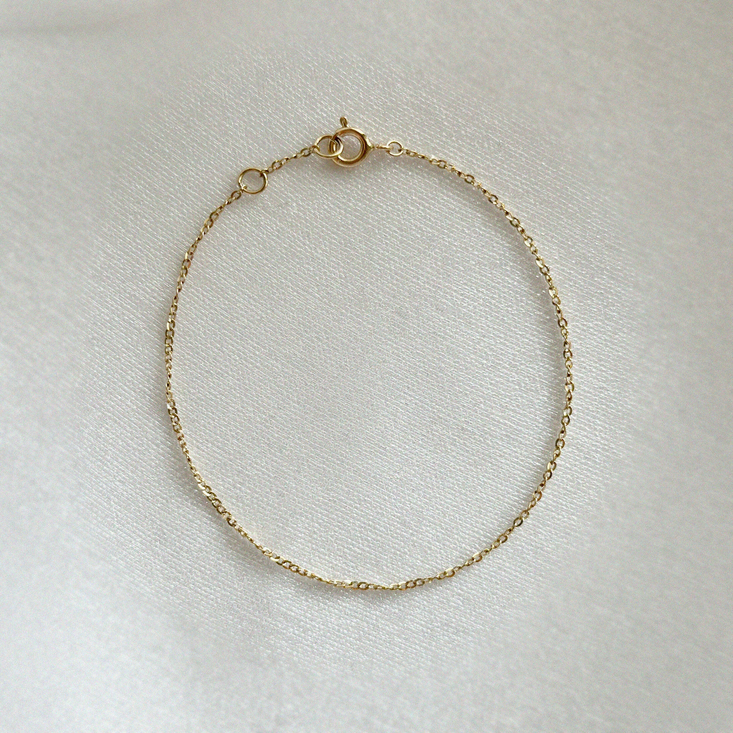 High polish twisted gold bracelet laid flat to show its radiant structure