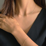 Model wearing matching 14K gold twisted chain necklace and bracelet, styled with a black V-neck top