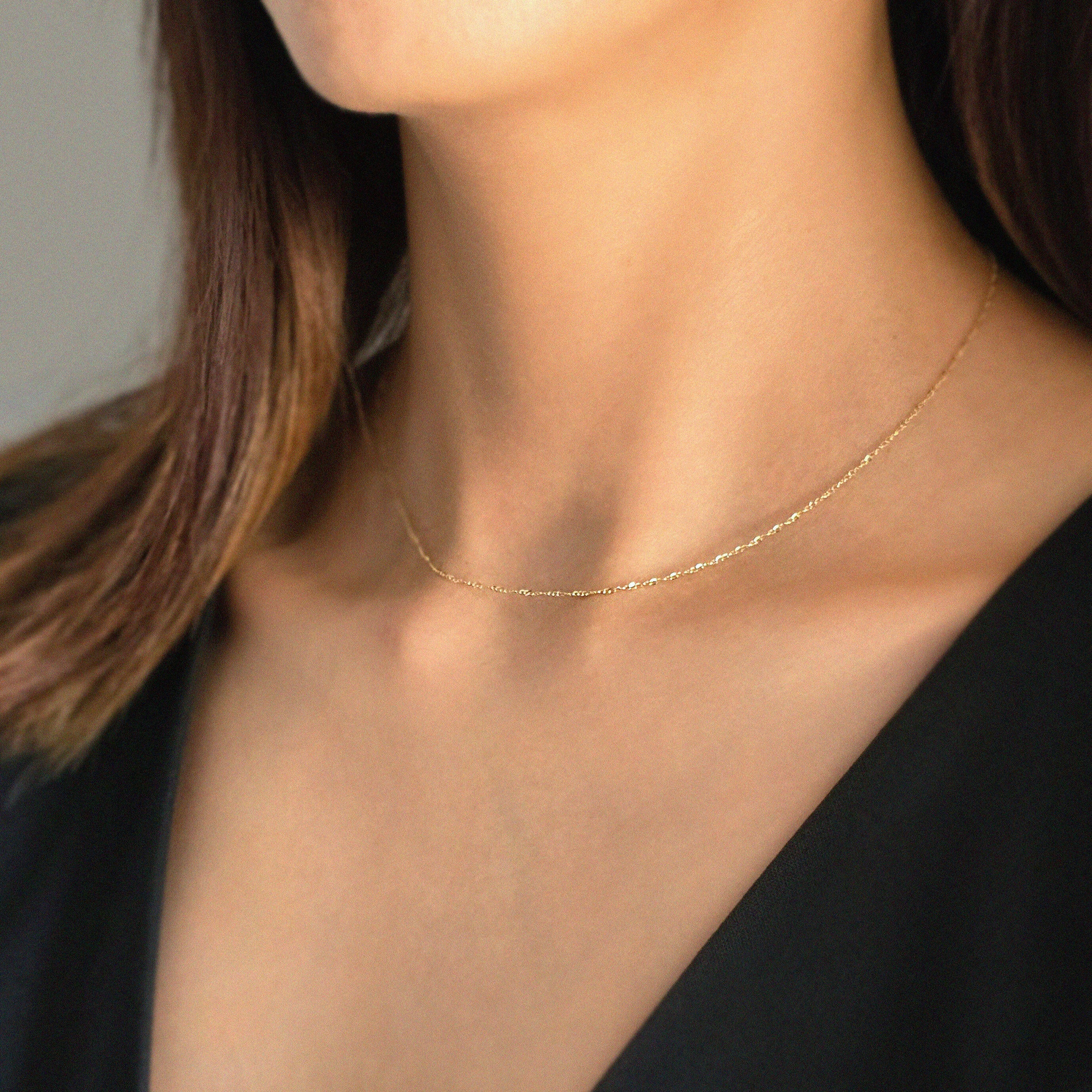 Model wearing the Torino Chain Necklace with V neck black top, showcasing its refined minimalism