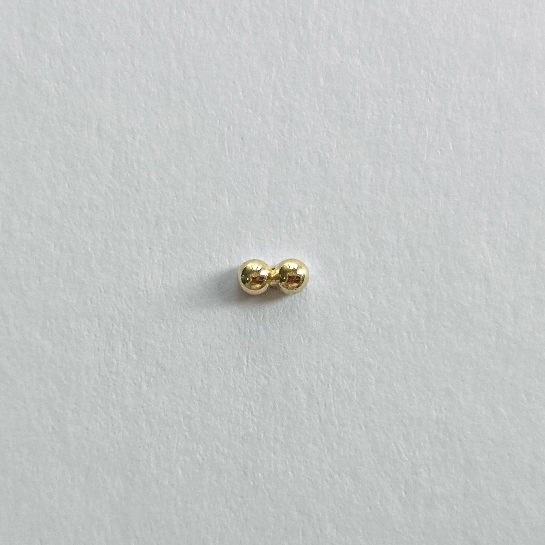Side view of 14K gold twin ball cartilage earring on white background