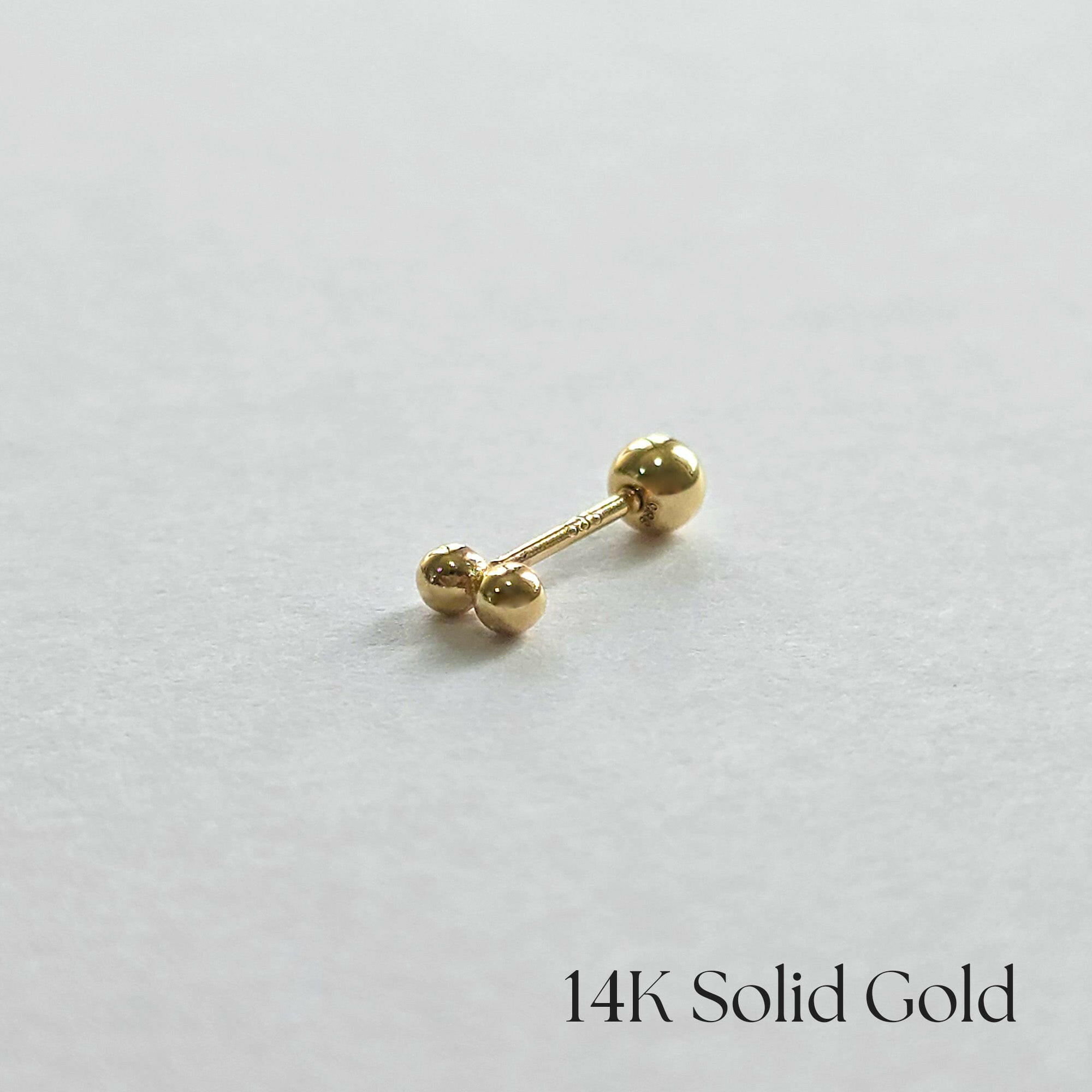 Side profile photo of 14K gold twin ball cartilage earring on white background