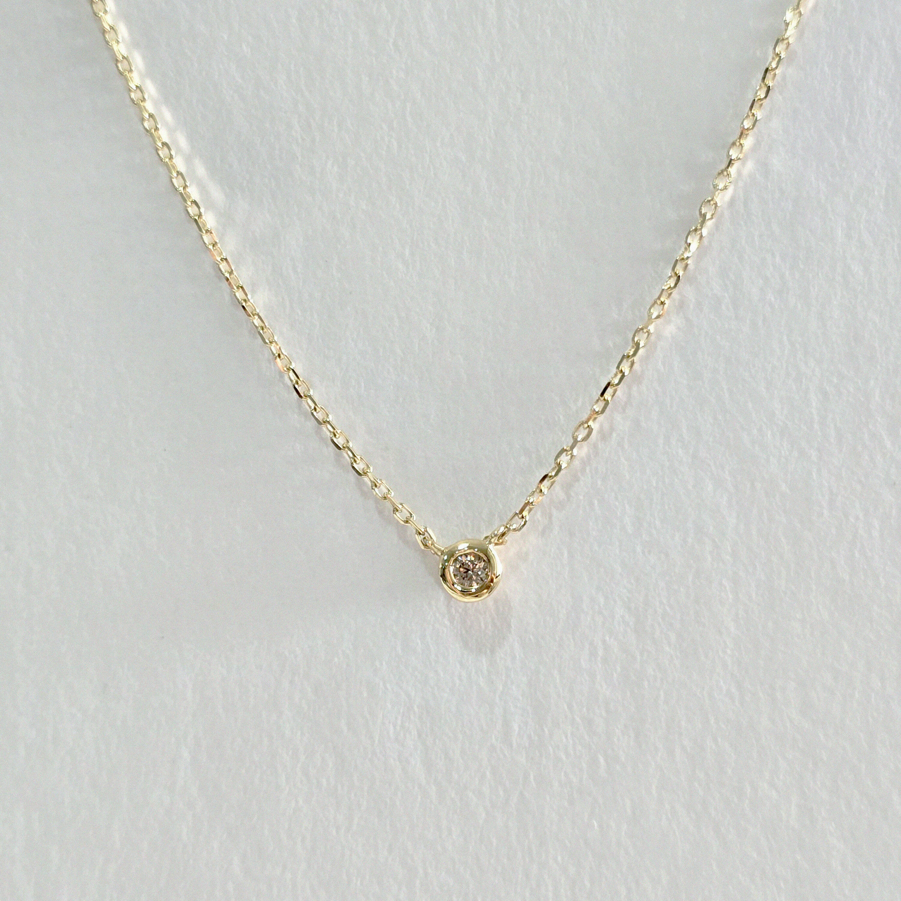 Close-up of bezel-set diamond pendant in 14K gold – radiant, minimalist design