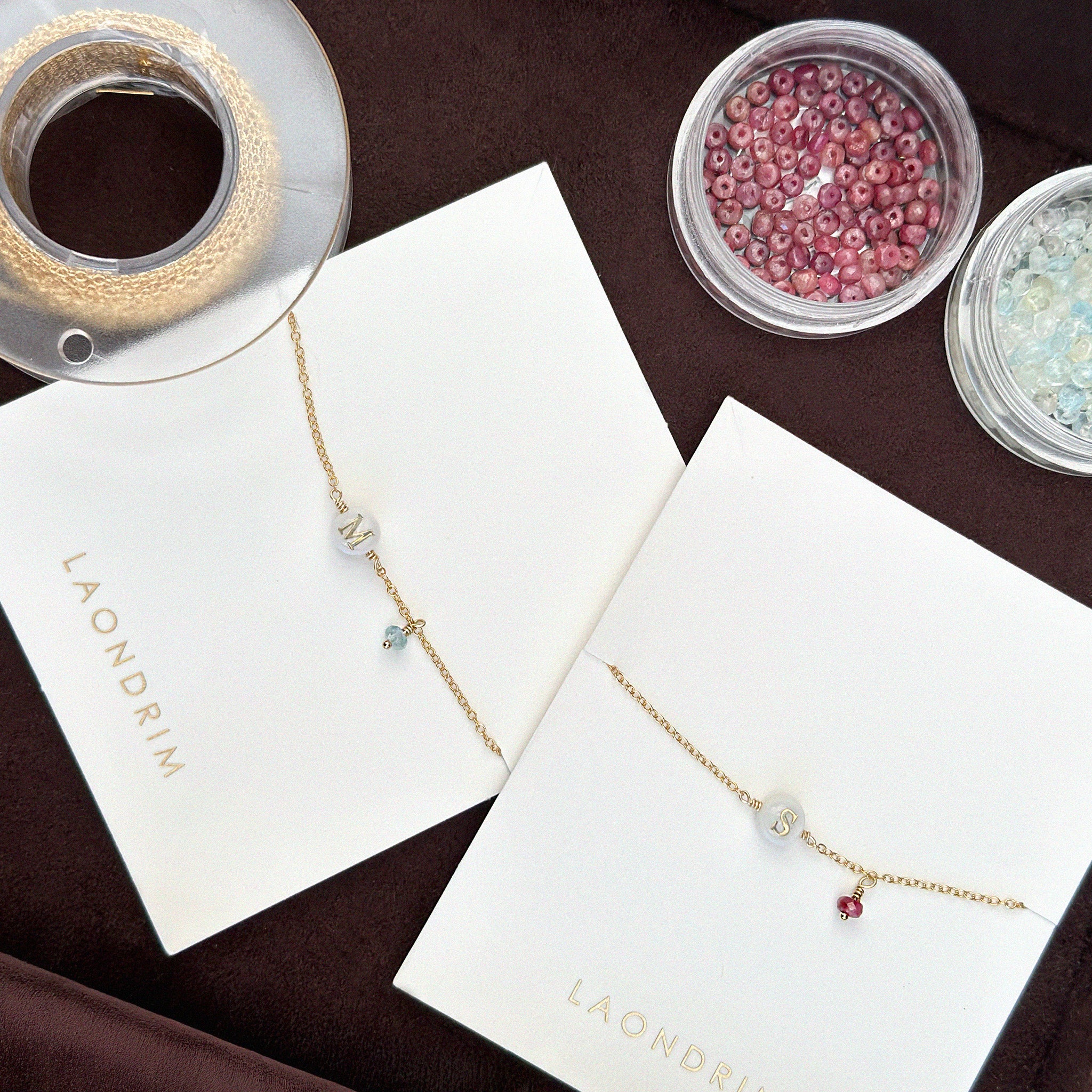 Necklace on display with 'Laondrin' branding, surrounded by small containers of beads.