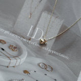 High-polish heart charm necklace in 14K gold with dainty cubic zirconia detail at the center, styled simply