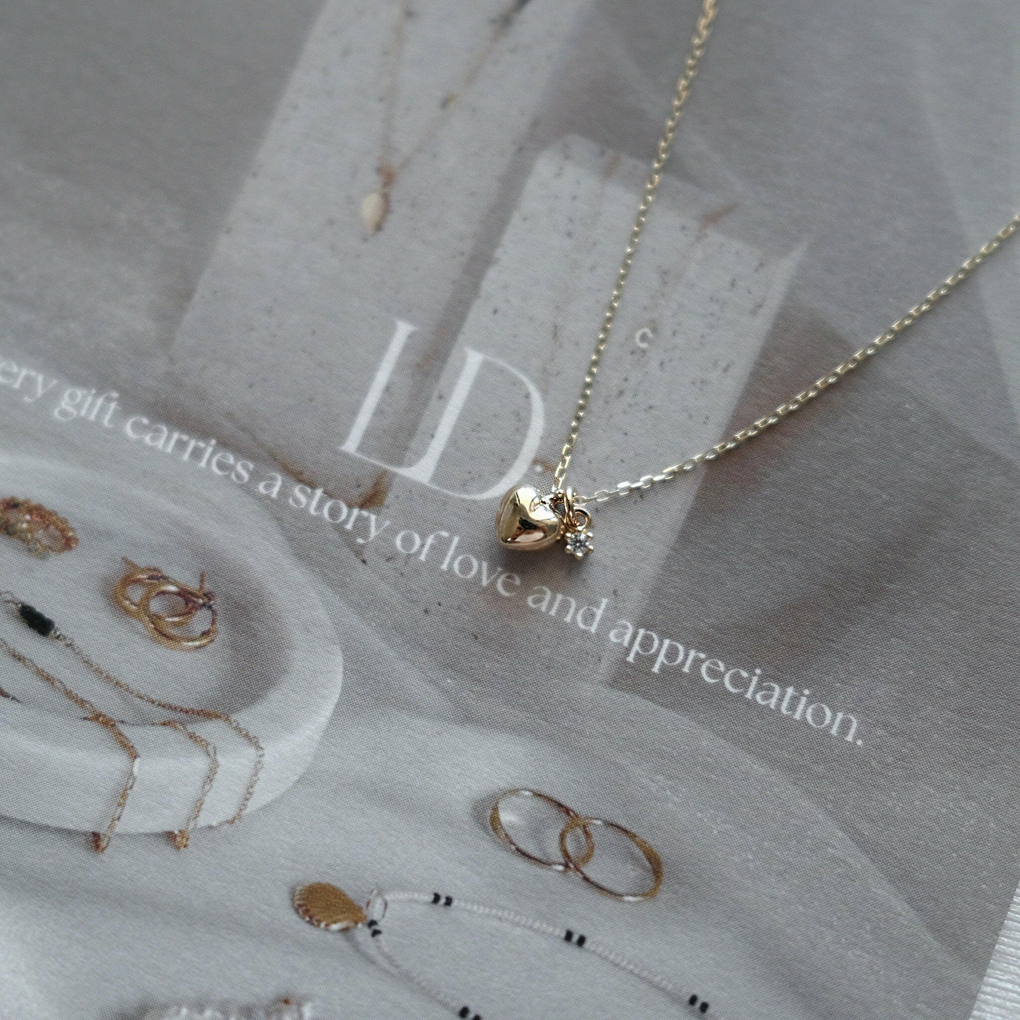 High-polish heart charm necklace in 14K gold with dainty cubic zirconia detail at the center, styled simply