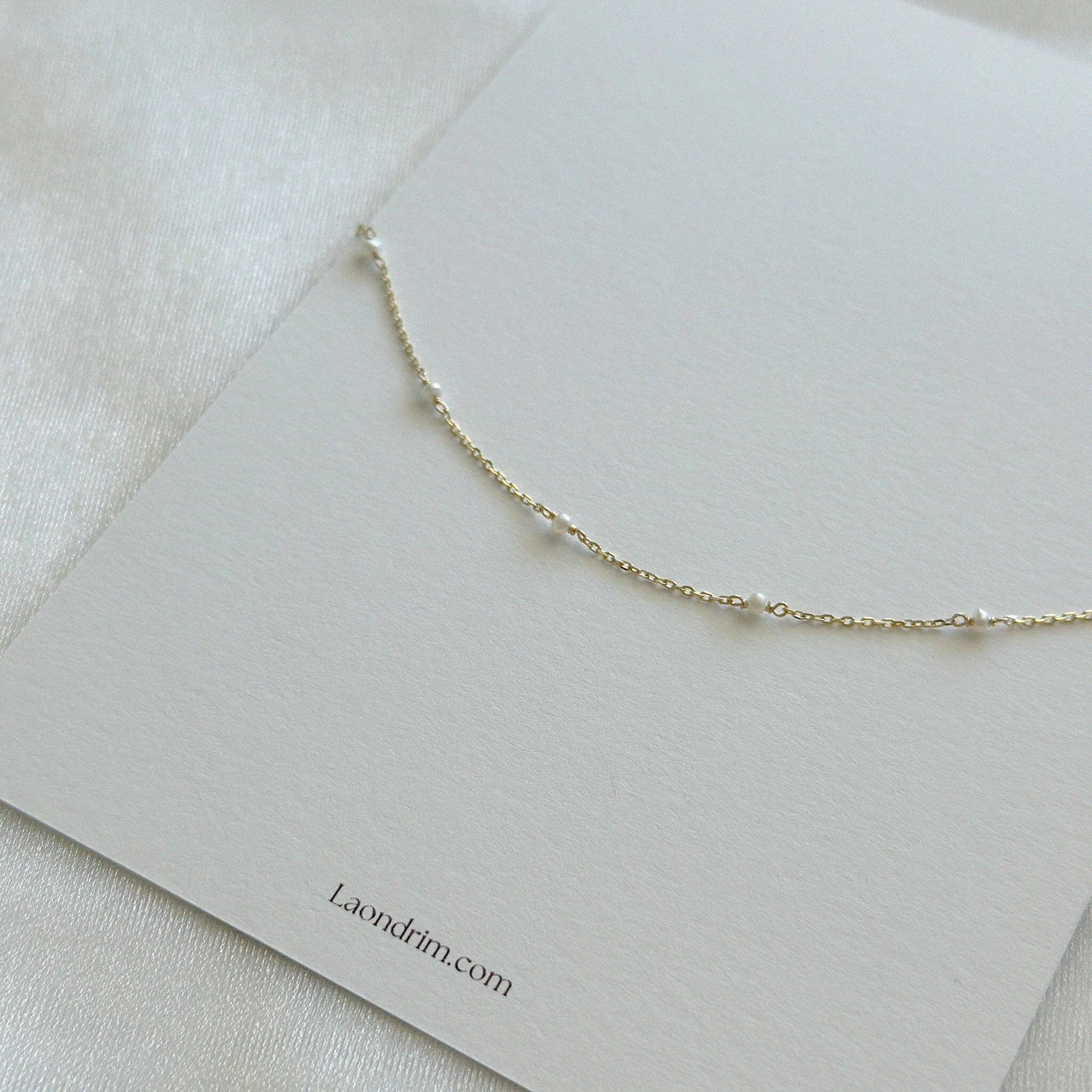 Elegant bracelet resting on textured surface with simple branded card