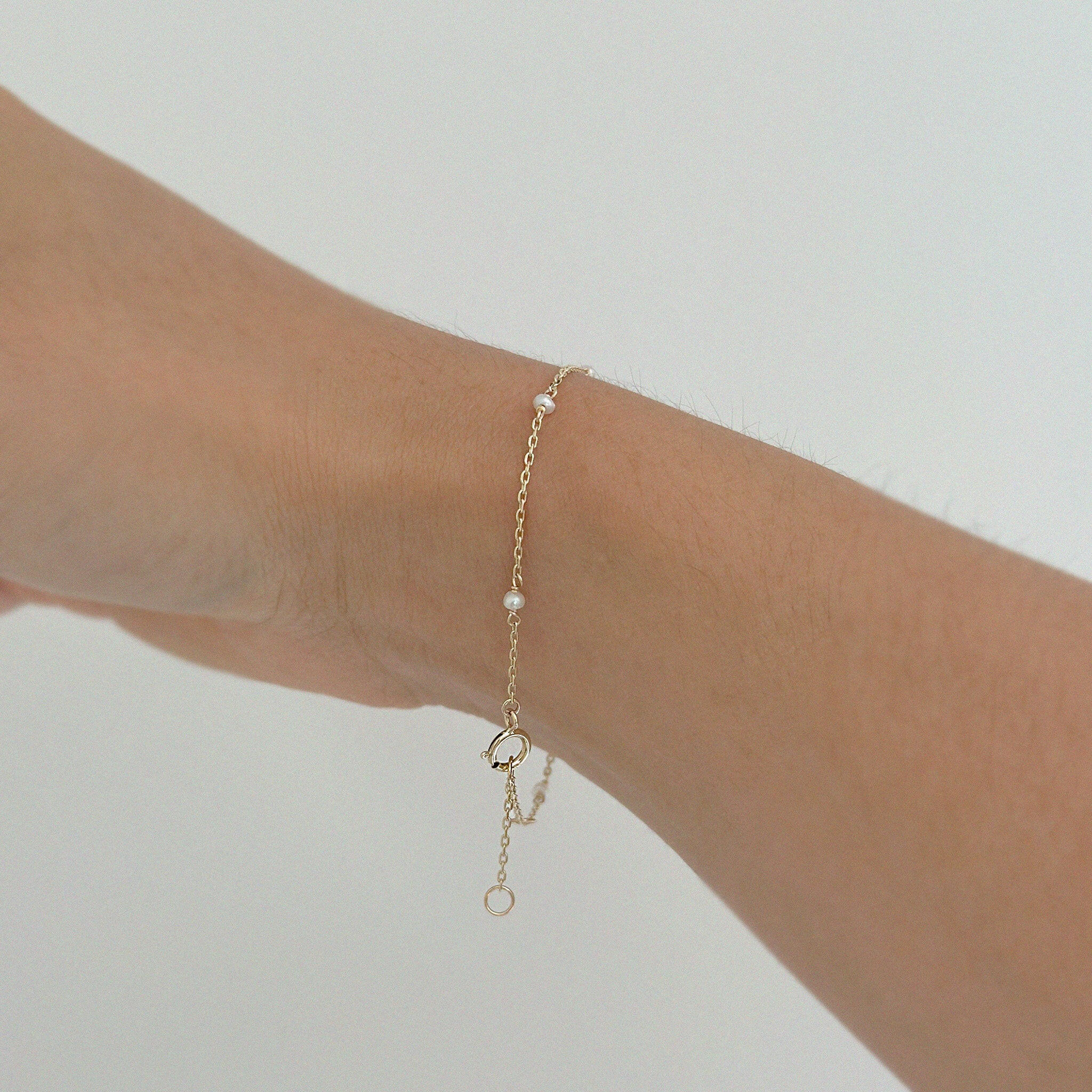 Freshwater pearl and gold chain bracelet gently draped on wrist