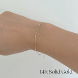 Model wearing Ariel’s Pearl Bracelet with layered gold jewelry on wrist