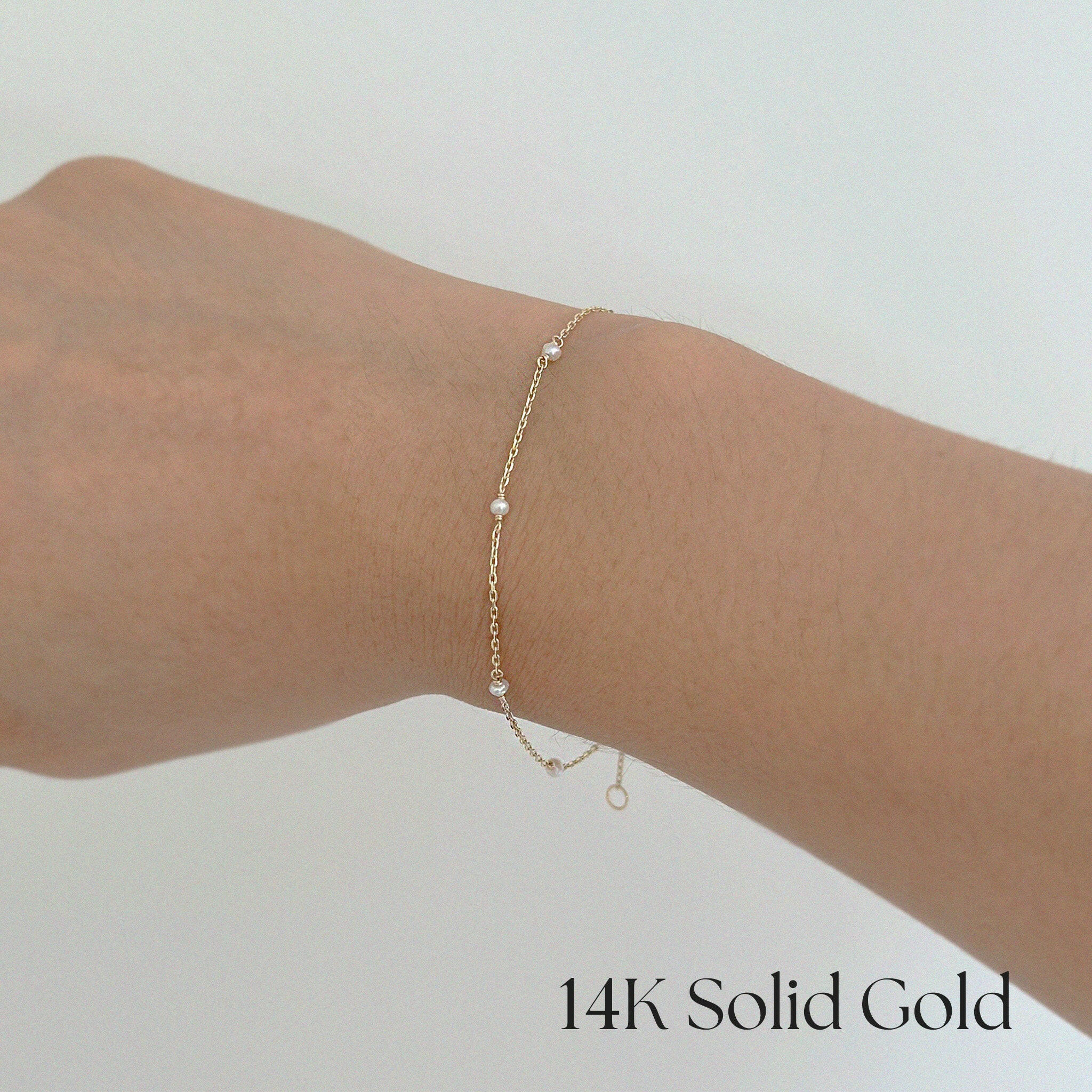 Model wearing Ariel’s Pearl Bracelet with layered gold jewelry on wrist