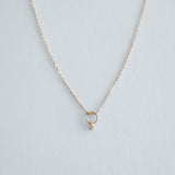 Overhead close-up showing the hammered texture of the 14K gold circle pendant and inset diamond