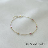 Delicate 14K gold bracelet with Pink Sapphire accents displayed flat