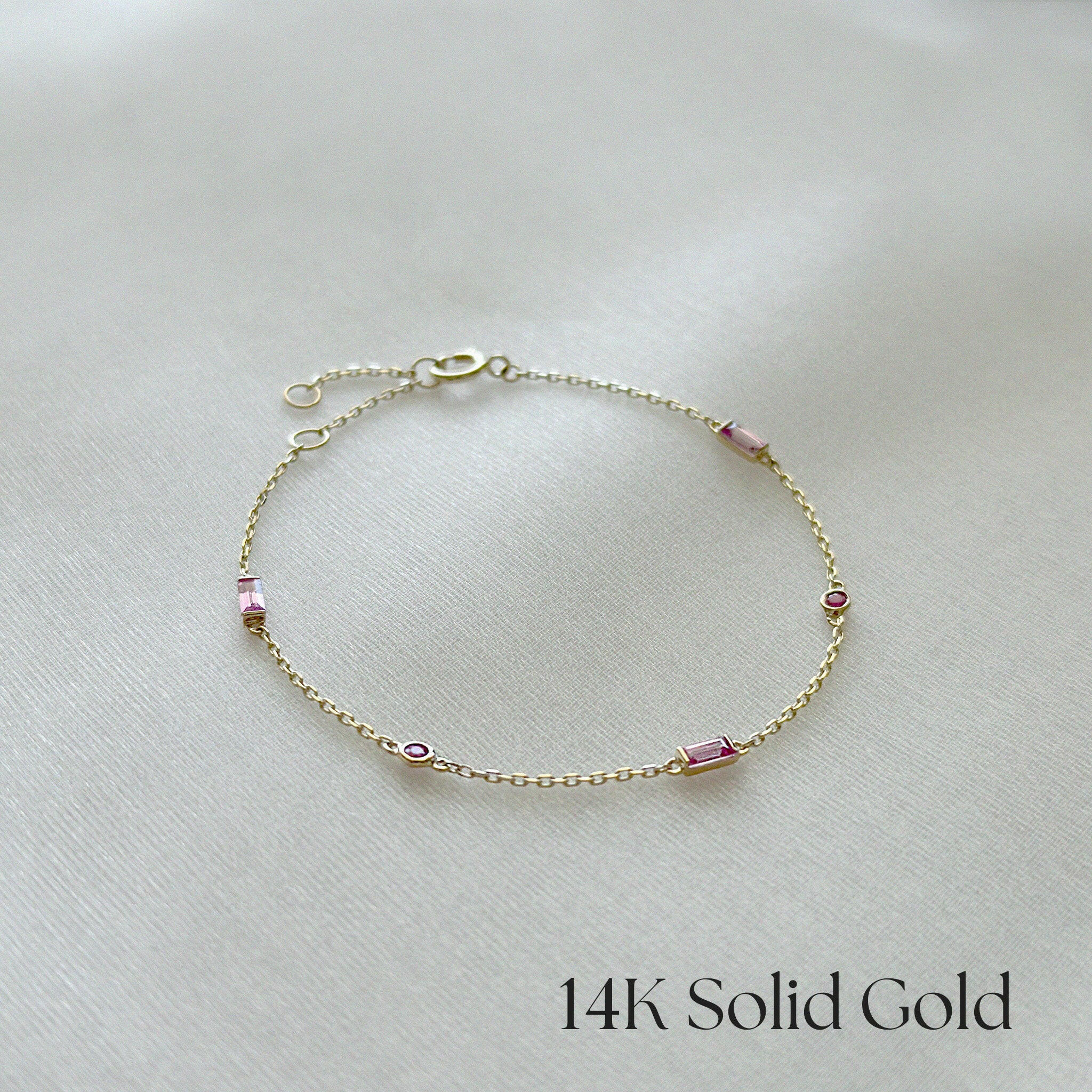 Delicate 14K gold bracelet with Pink Sapphire accents displayed flat