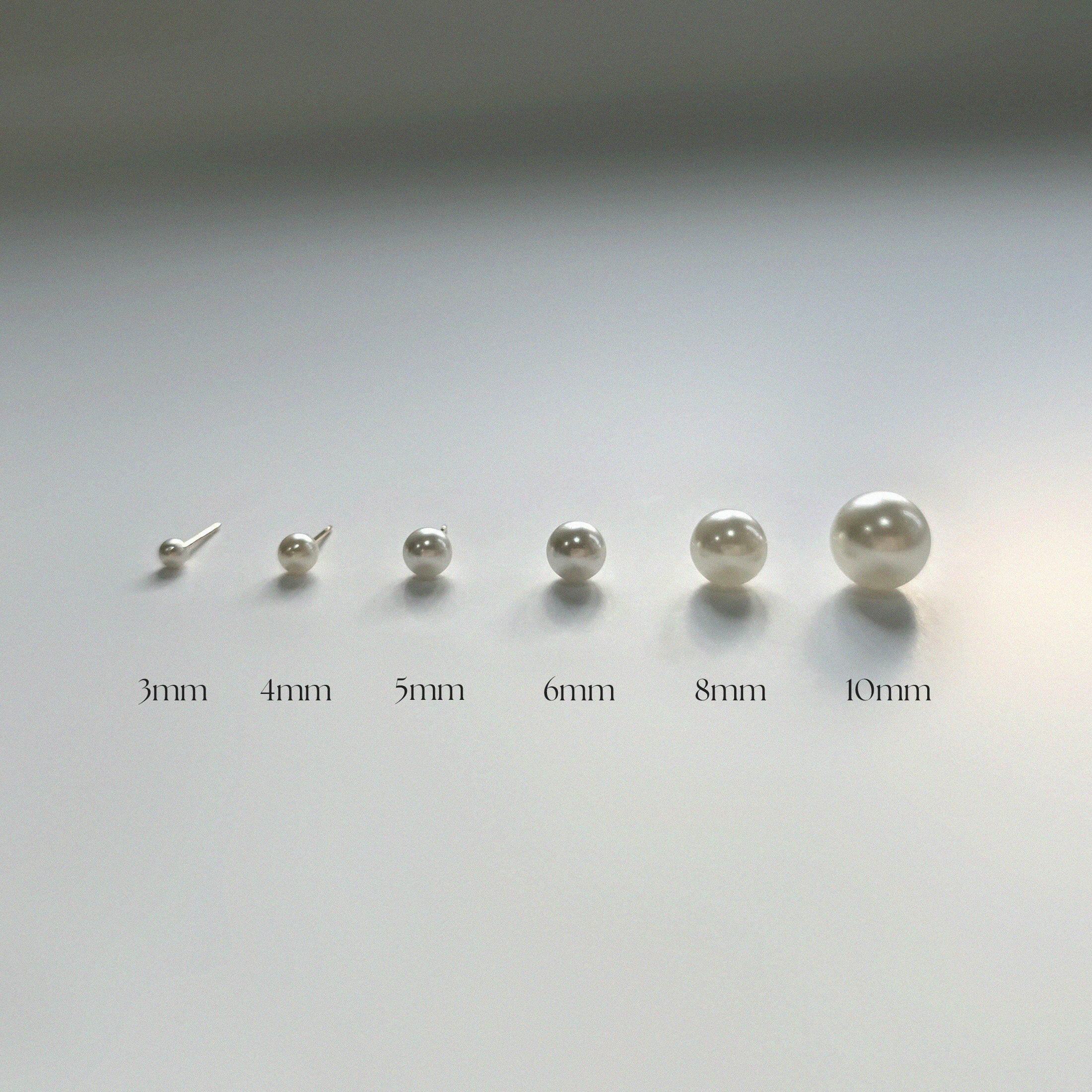 Front view of minimalist freshwater pearl stud earrings in 6 different sizes