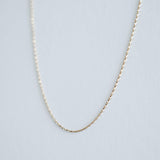 Oblique view of the 14K gold box chain showing how light catches its textured surfaces