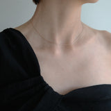 Model wearing the Twist Box Chain Necklace over a black off-shoulder top for a minimal yet striking contrast