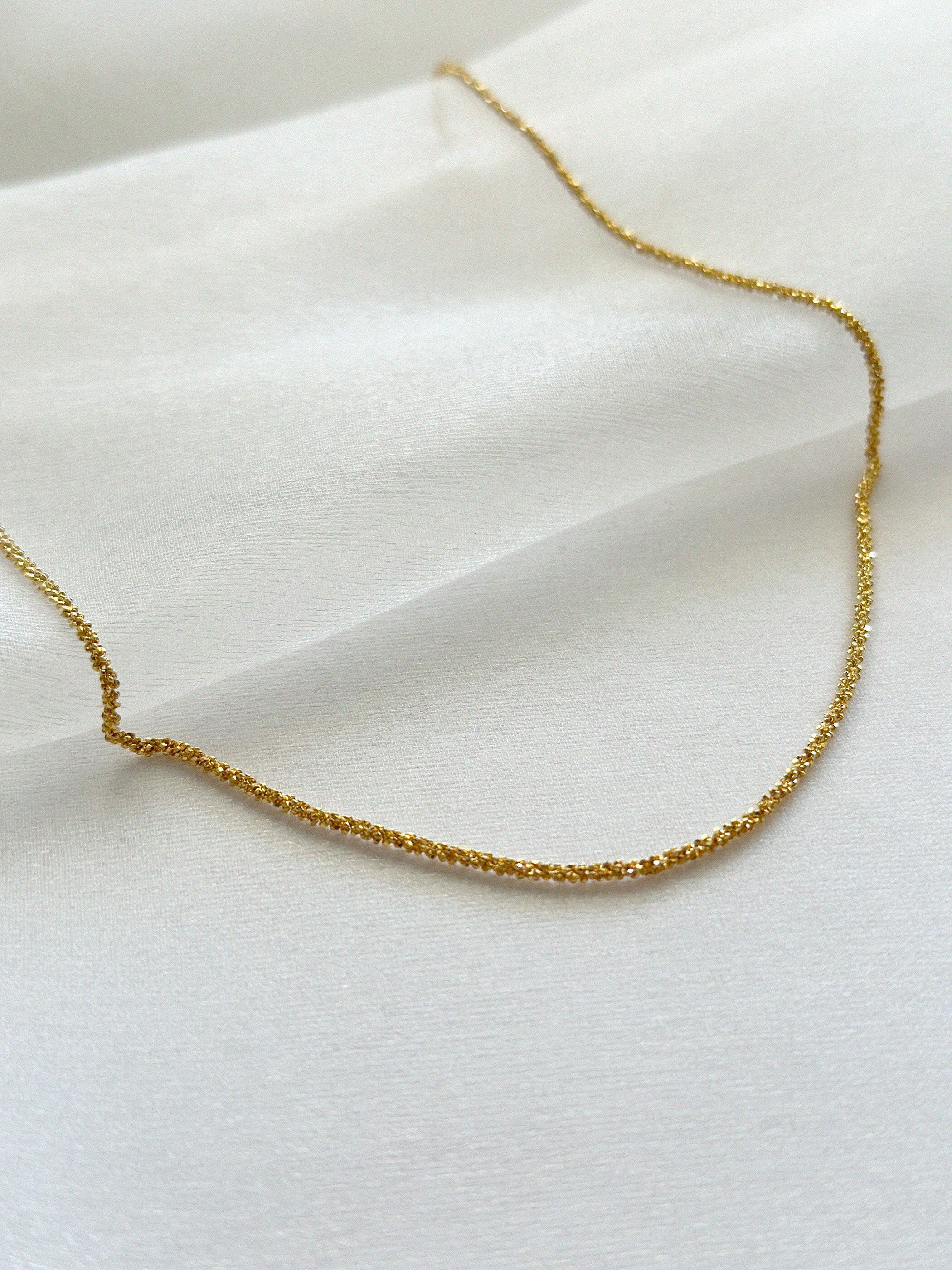 Close-up of sterling gold basa necklace on shimmery soft fabric