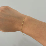 Top view of fine gold bracelet styled solo on model’s wrist