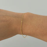 Top view of fine gold bracelet styled solo on model’s wrist