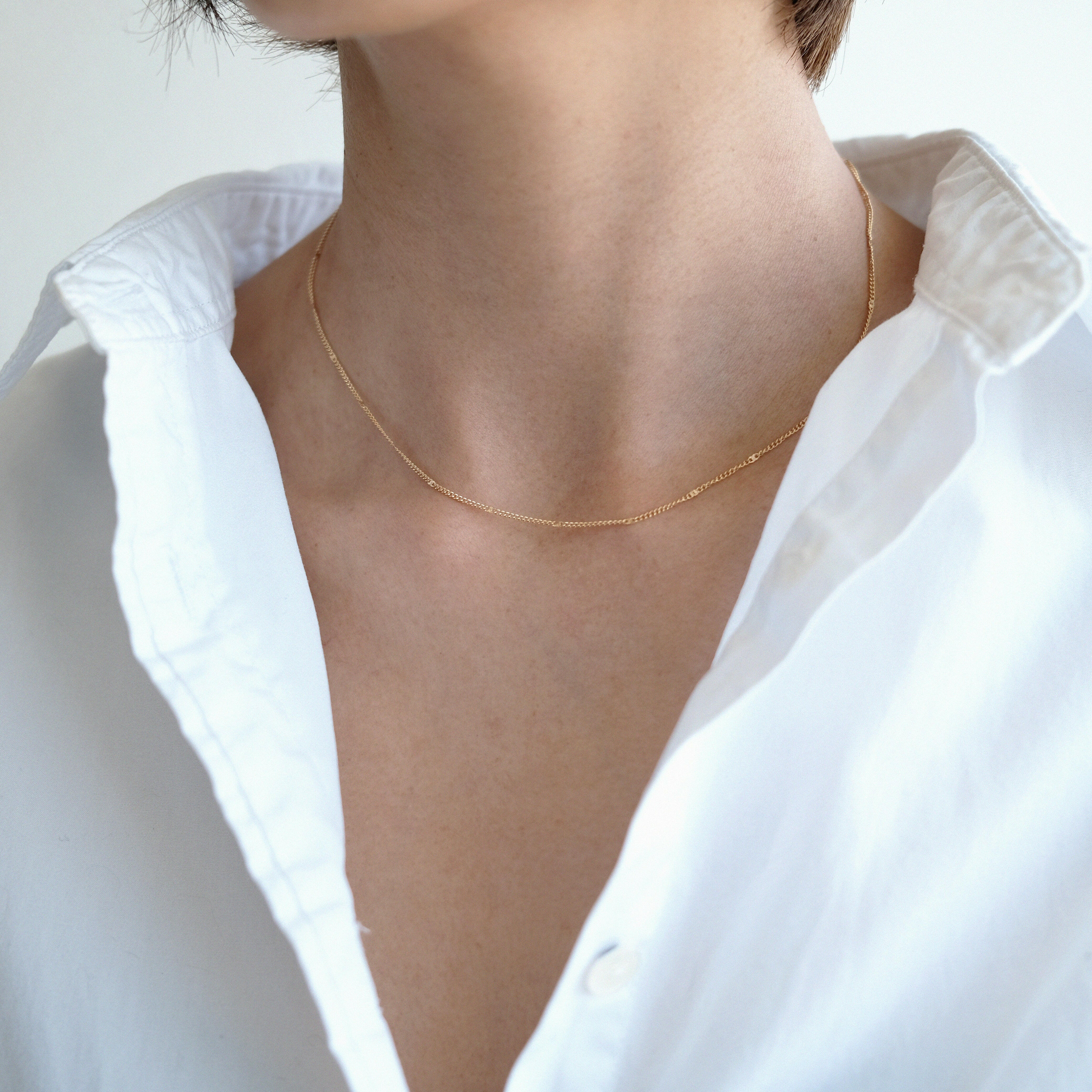 Solo styling with chain sitting on collarbone in white shirt