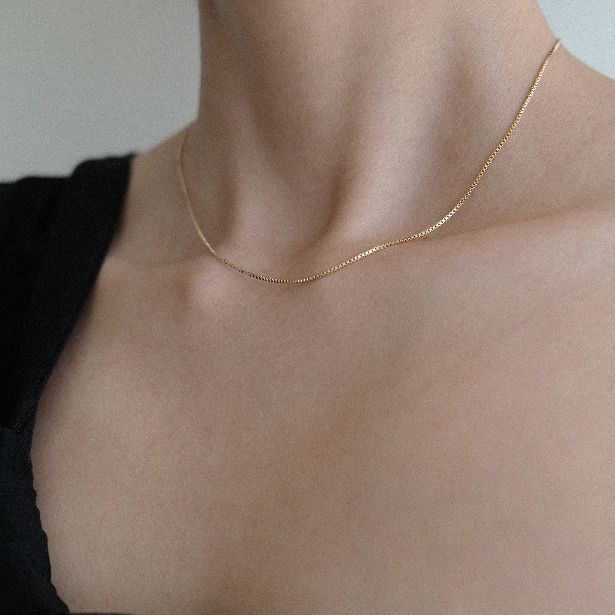 Model wearing box chain necklace alone on black shirt