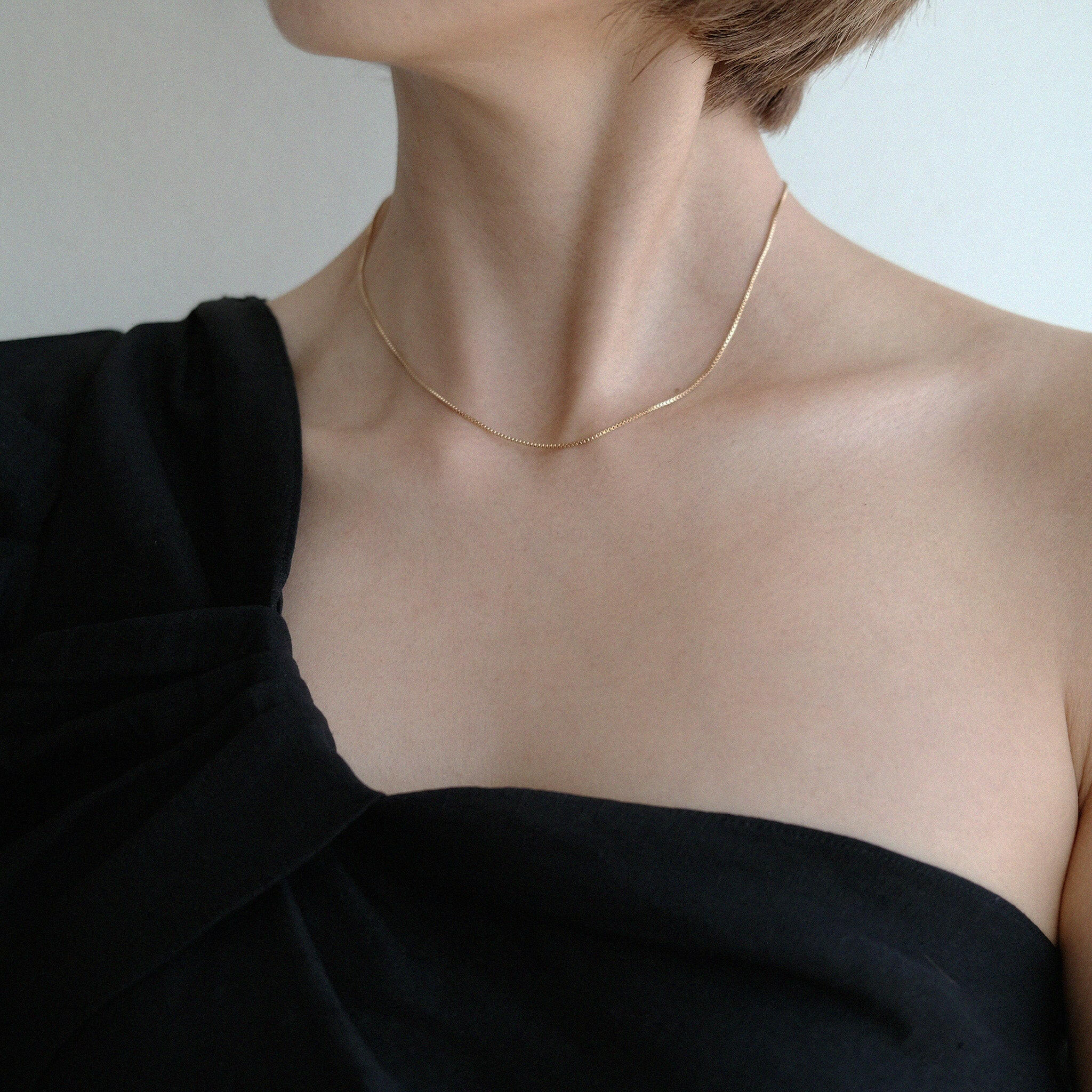 Model wearing box chain necklace alone with minimalist outfit