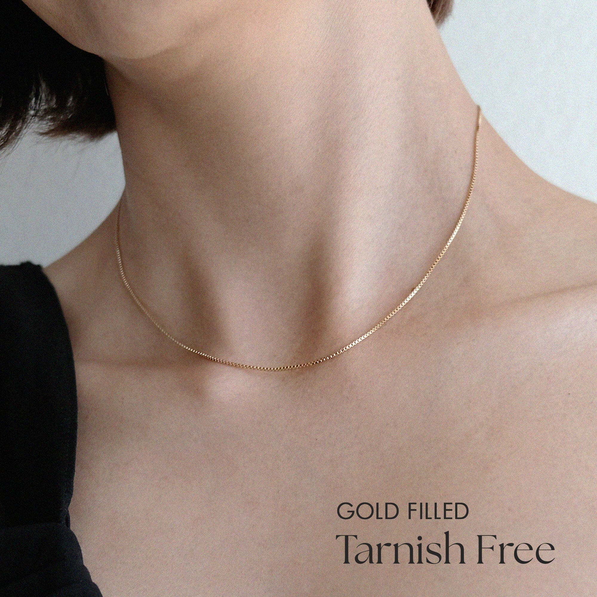 Model wearing box chain necklace alone with minimalist styling
