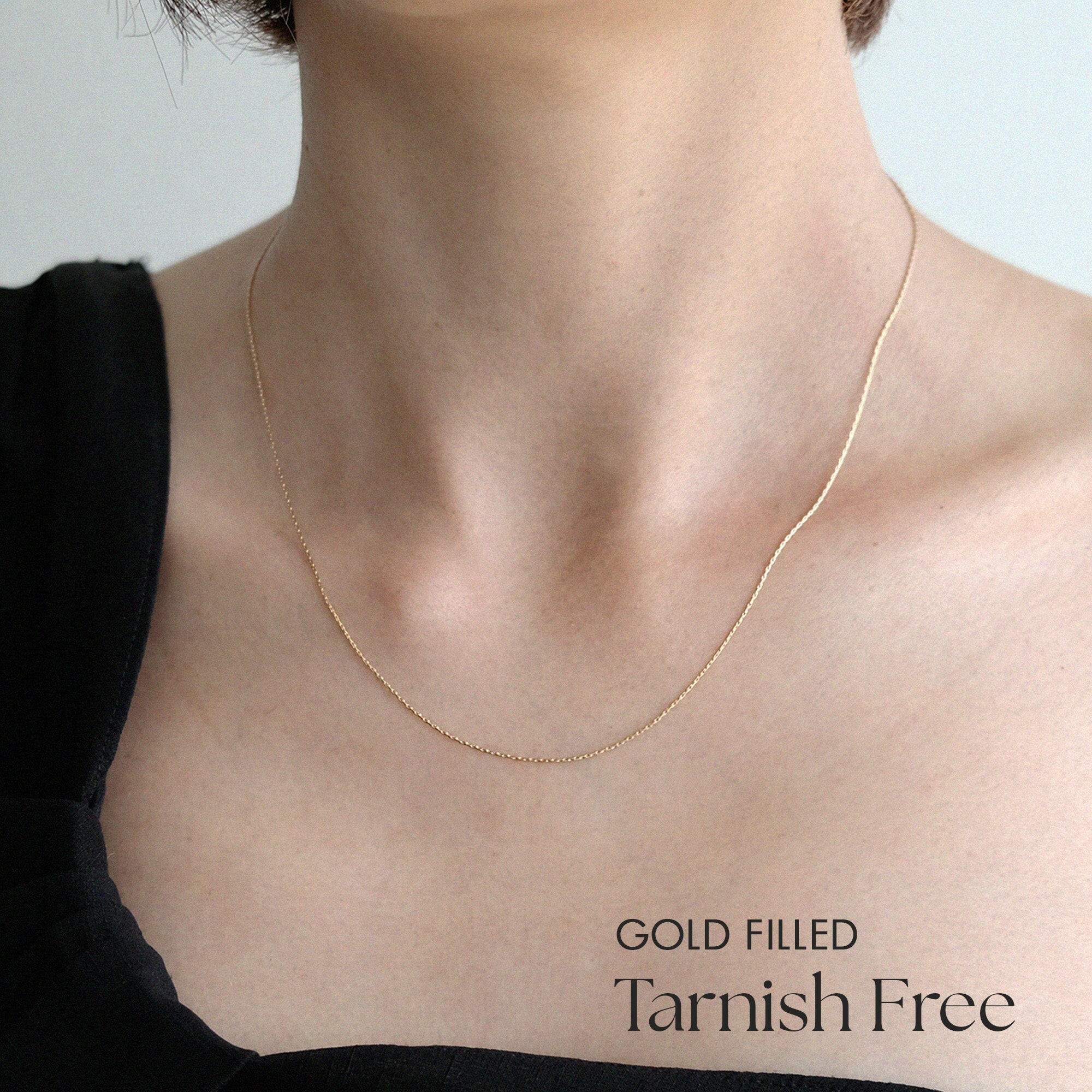 Model wearing cable chain necklace alone with minimalist outfit