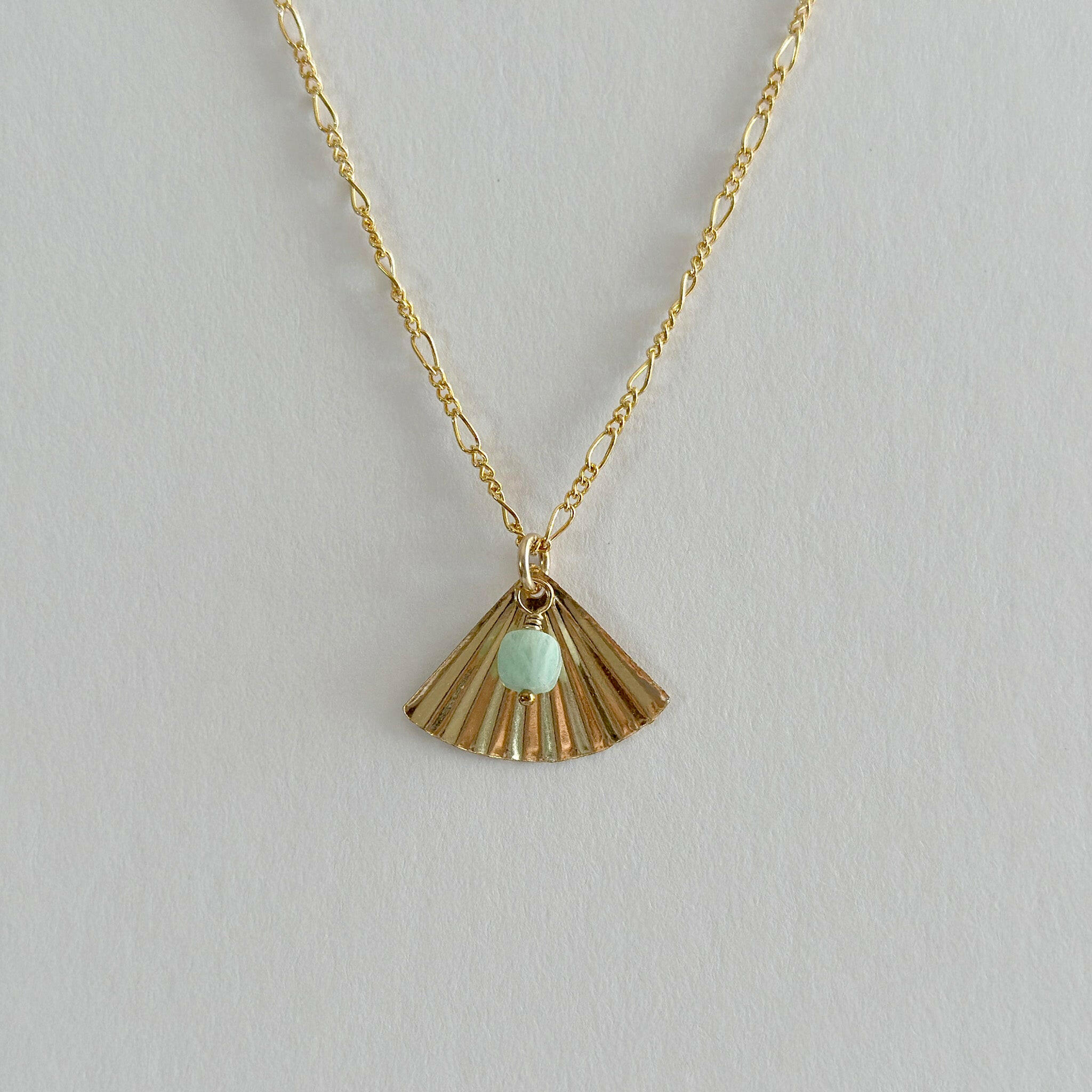 Close-up of fan-shaped gold pendant with soft green amazonite detail
