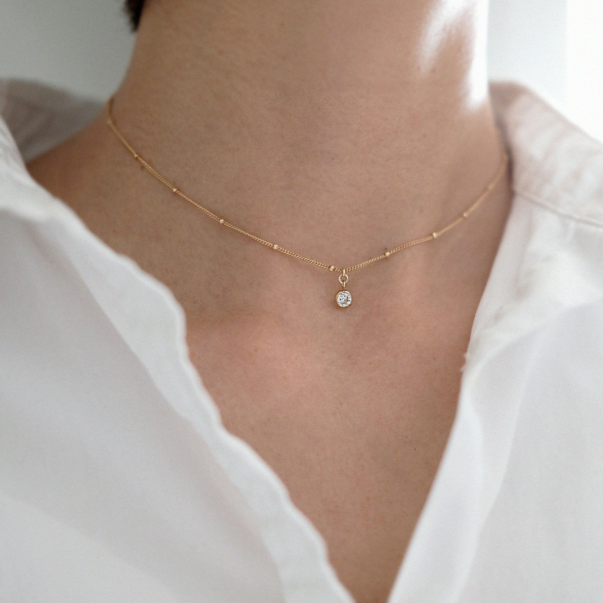 Model wearing crystal accent necklace with minimal makeup and neutral outfit