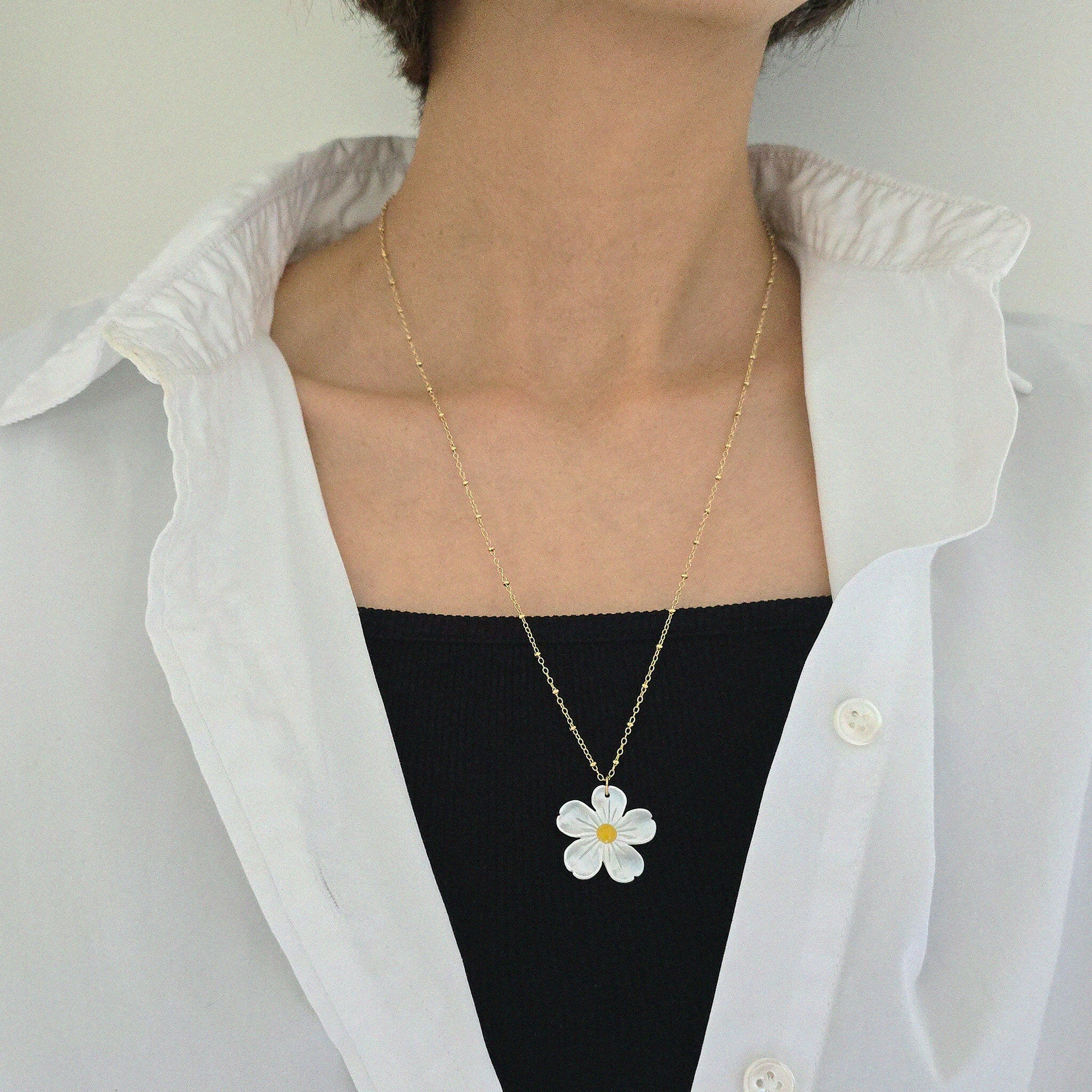 Model wearing daisy necklace as a statement piece on a plain top