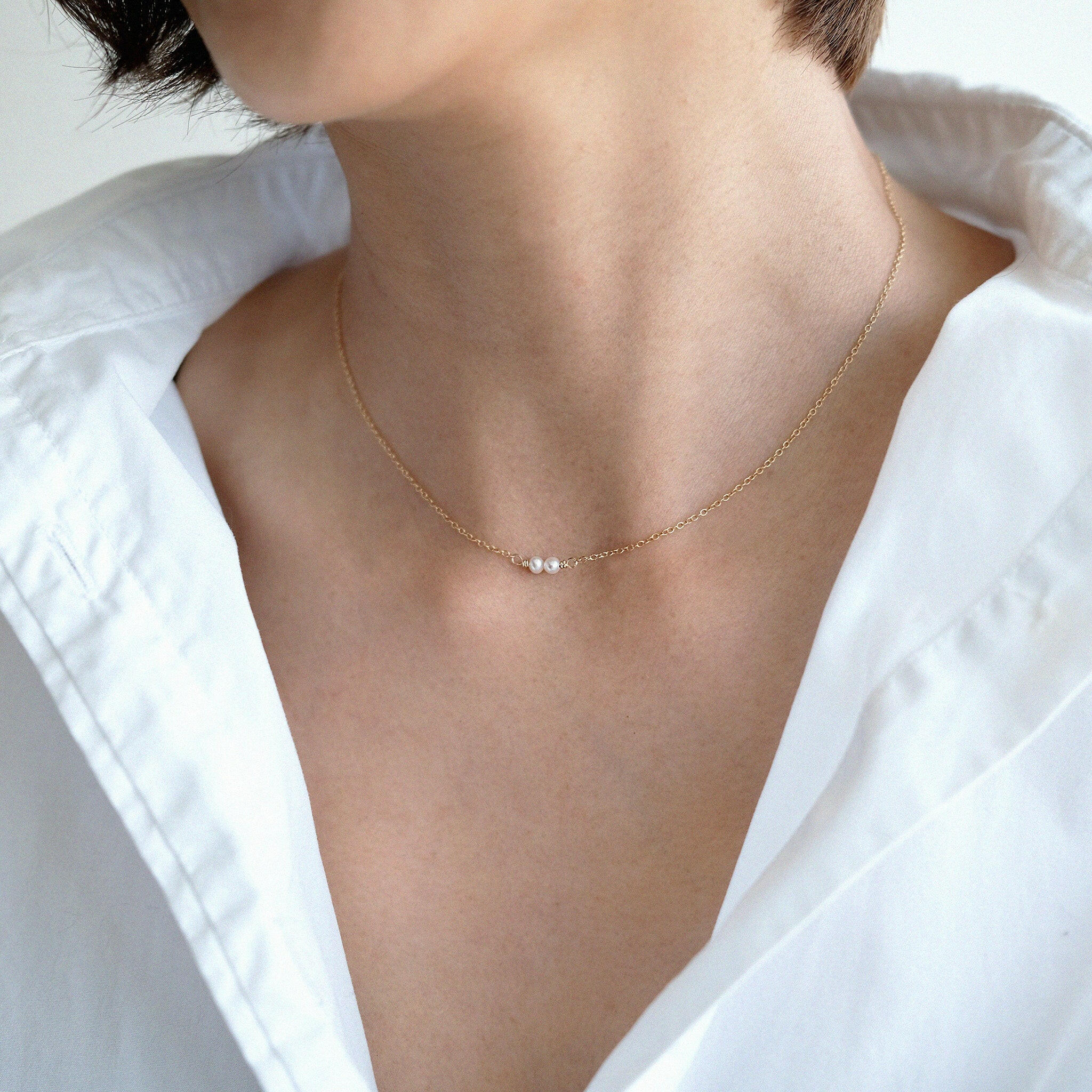 Model wearing double pearl necklace alone for minimalist style