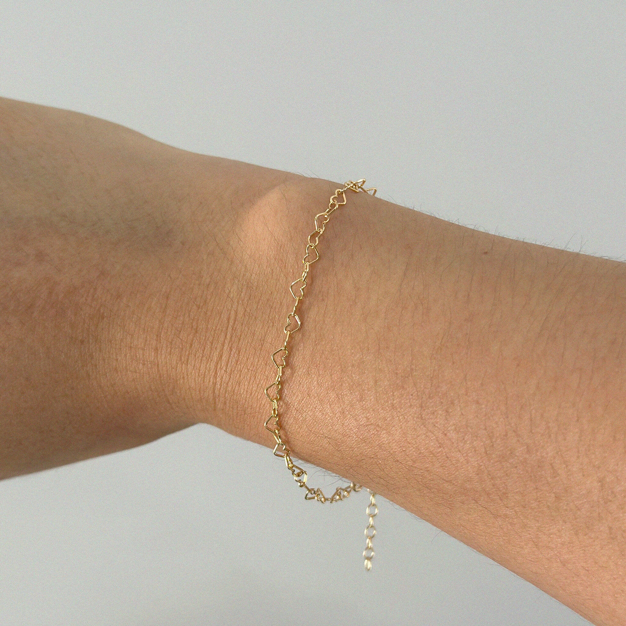 Bracelet worn on wrist viewed from above, showcasing linked hearts and slim profile