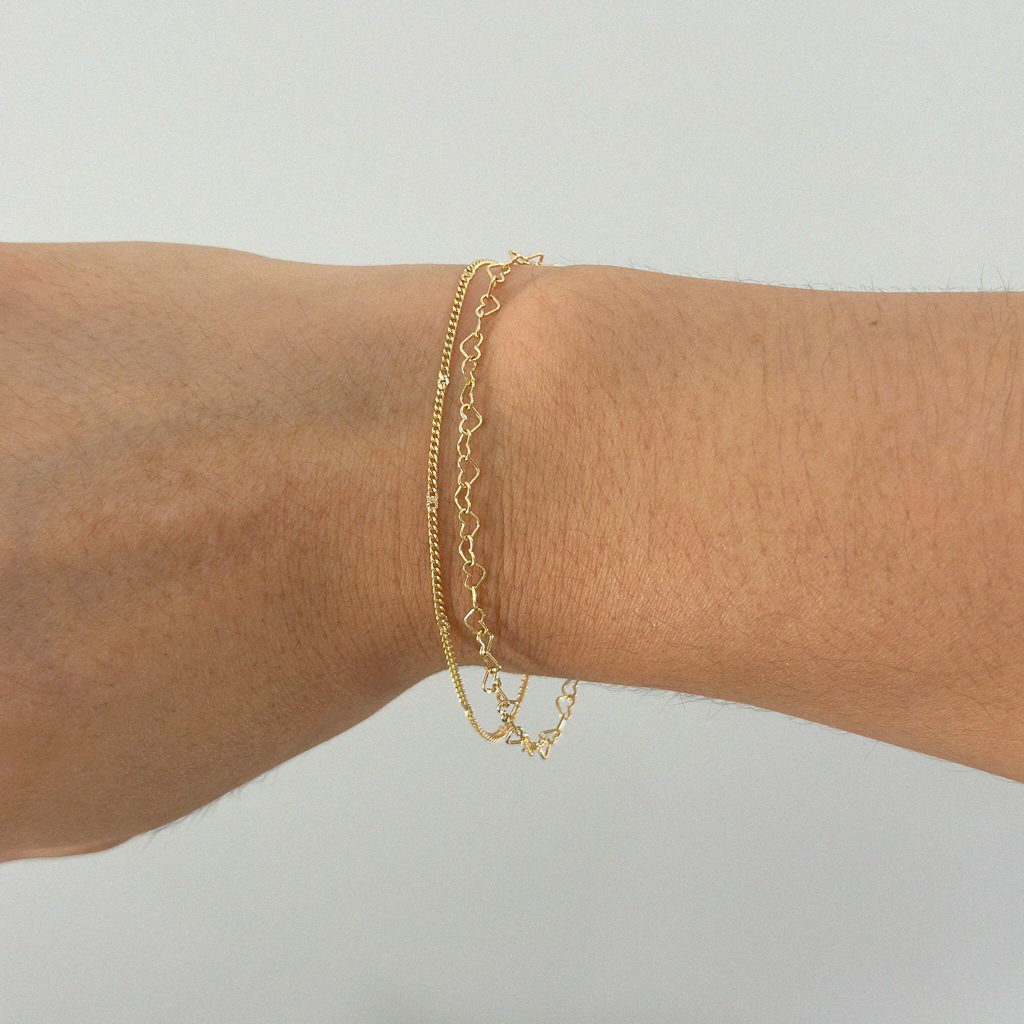 Linked heart bracelet layered with thin gold chain bracelet for stacked wrist look