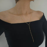 Gold necklace worn by a person in a black off-shoulder top against a neutral background