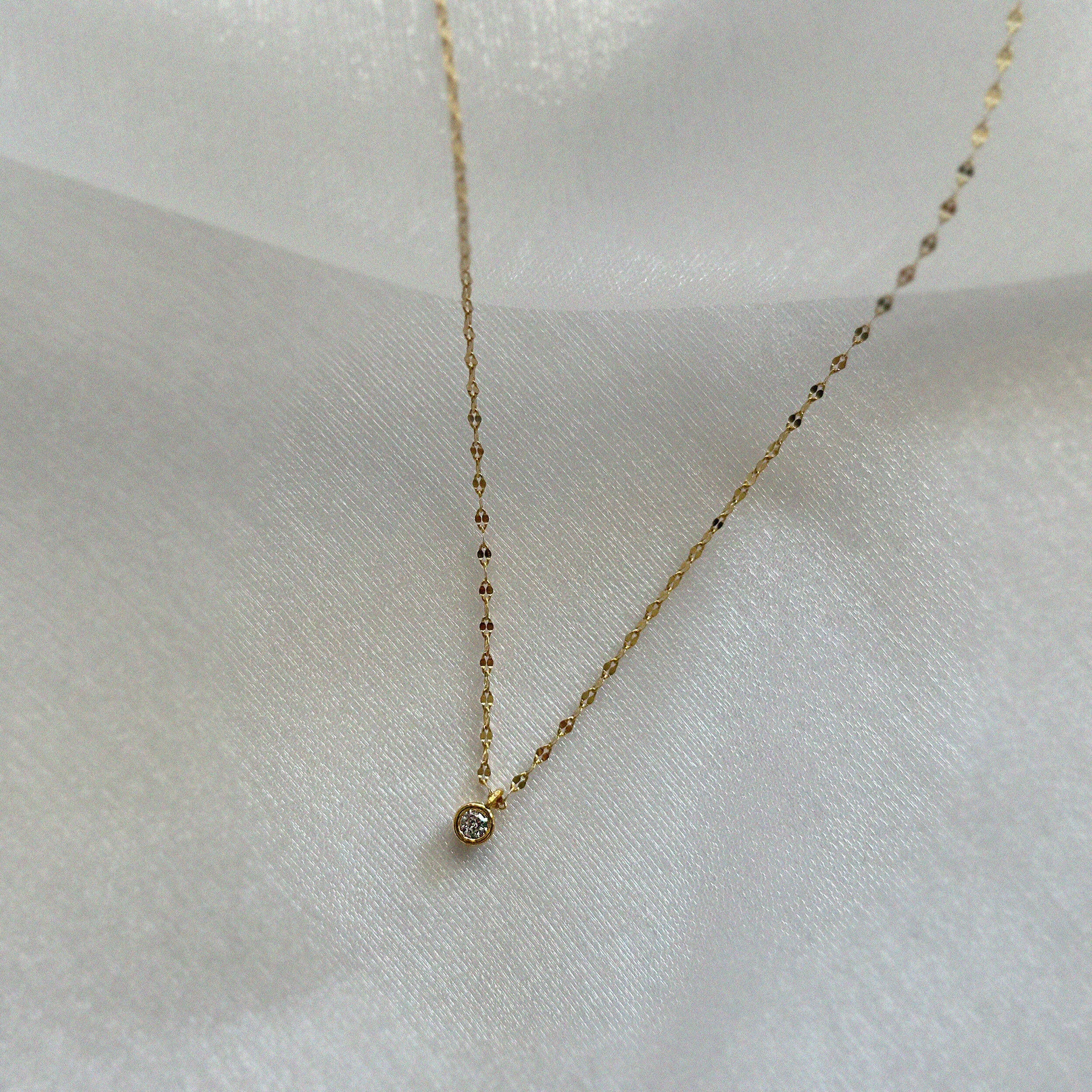 Crystal accent necklace resting on a beige fabric tray, showcasing its refined shimmer