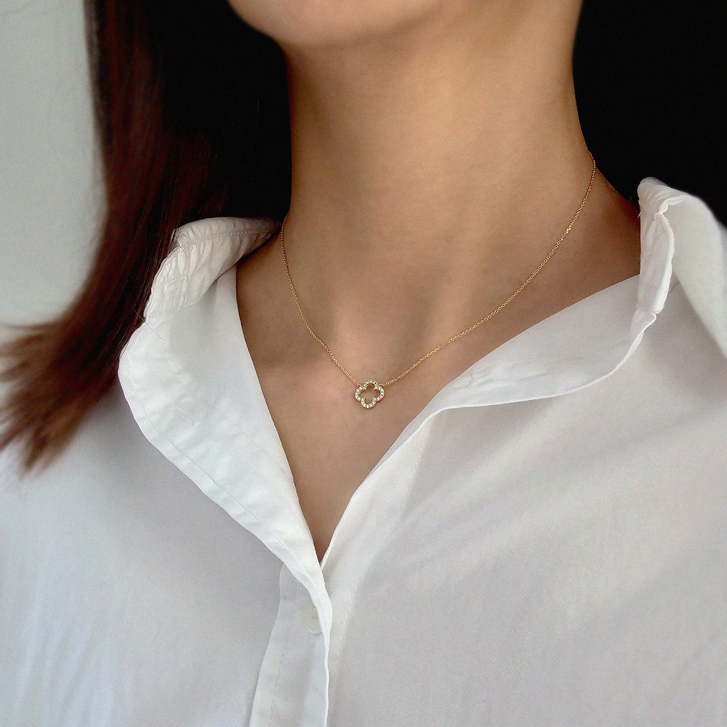 Model wearing 10mm clover pendant necklace in gold with open neckline