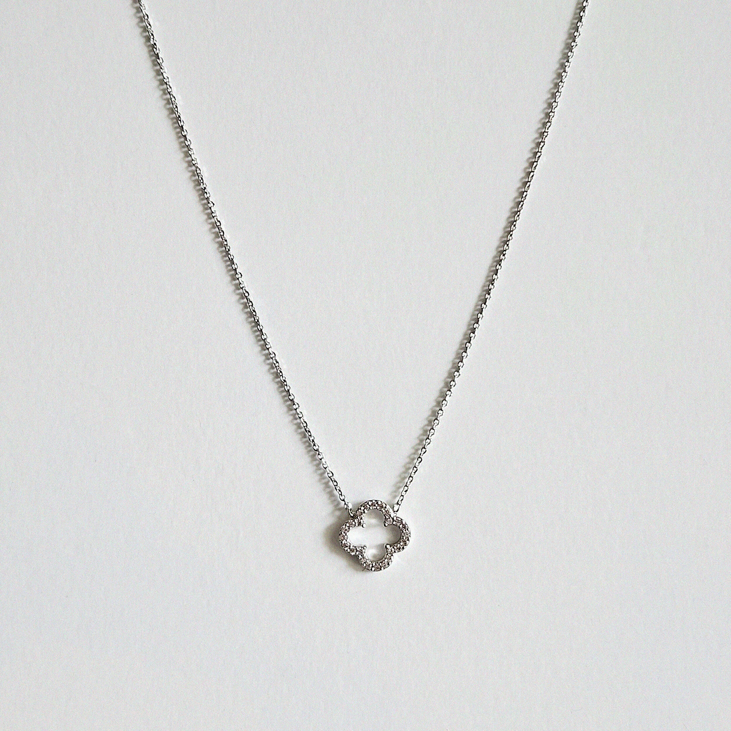 Crystal clover silver necklace with sparkling pendant laid flat in a soft curve