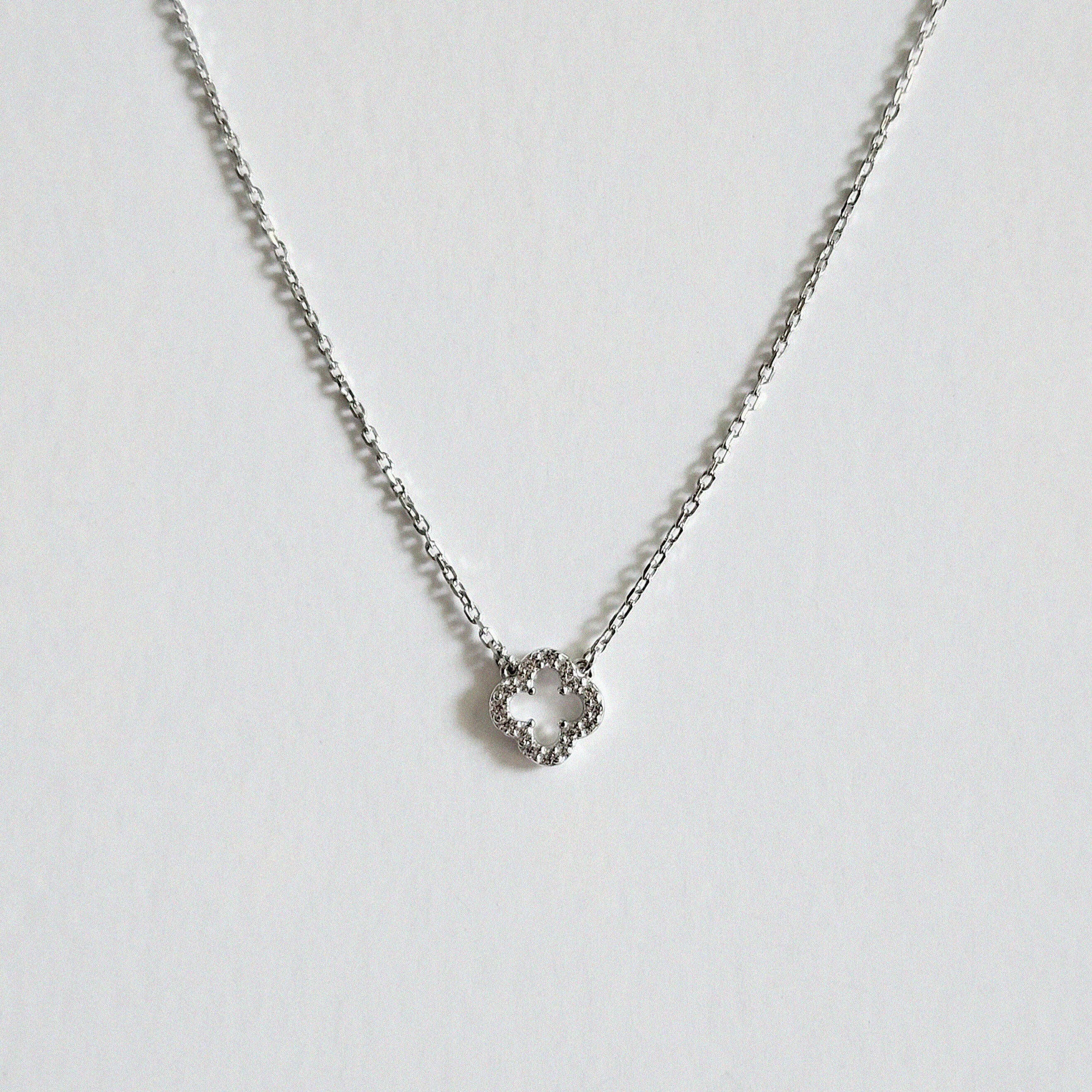 Close-up highlighting the four-leaf shape and crystal sparkle with dainty chain