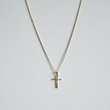 New Cross Necklace in gold laid flat featuring a sleek, rectangular cross pendant on a fine chain