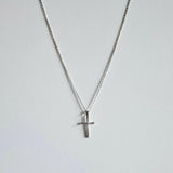 New Cross Necklace in silver laid flat featuring a sleek, rectangular cross pendant on a fine chain