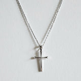 Close-up of rectangular silver cross pendant on a fine chain