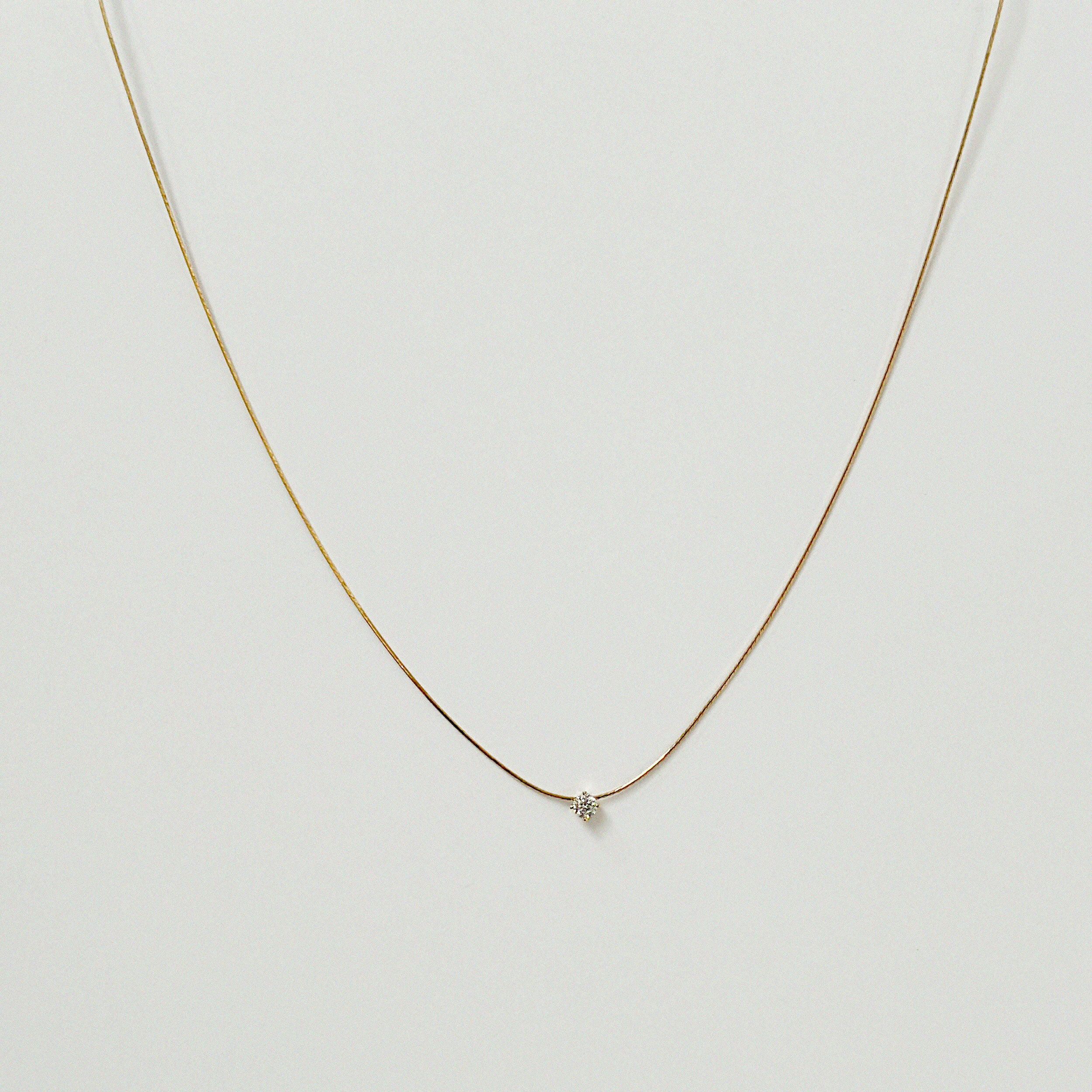 Petite crystal snake chain necklace in gold laid flat in a delicate curve with cubic zirconia accent.