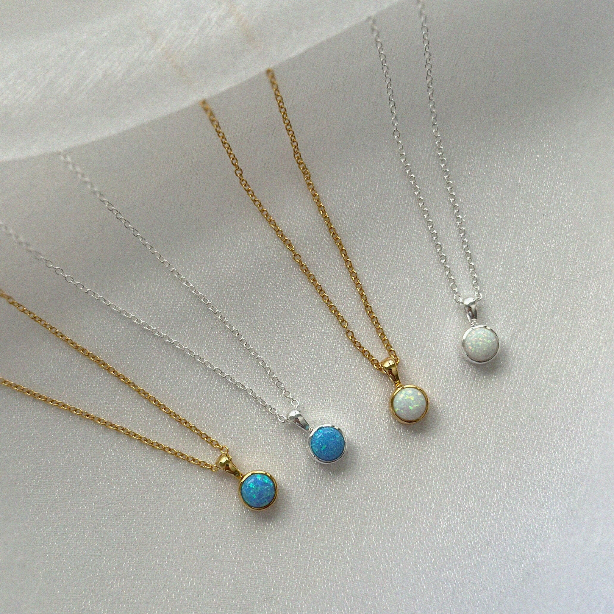 White and blue opal pendants necklaces displayed side by side
