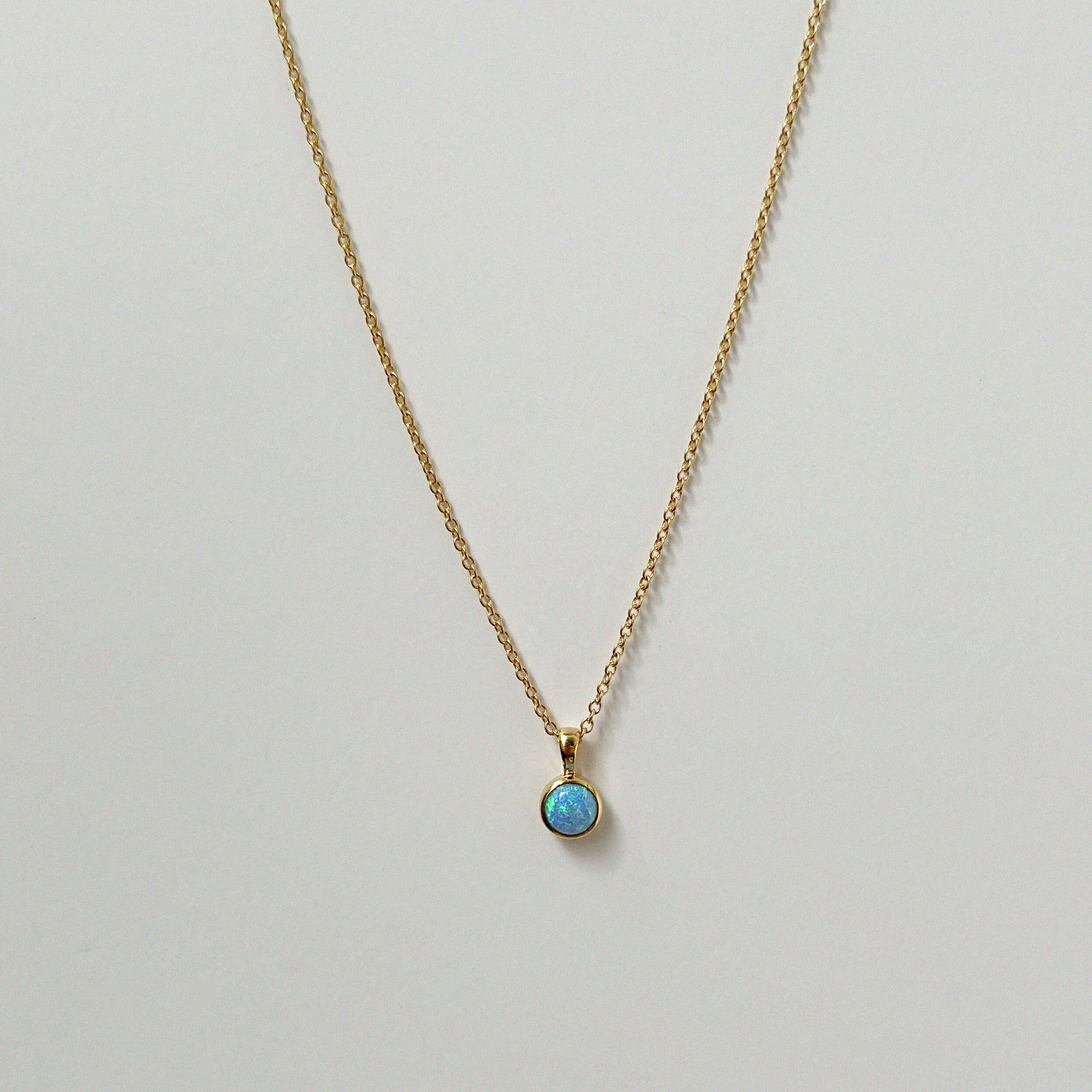 Delicate circular blue opal necklaces arranged in a minimal flat lay