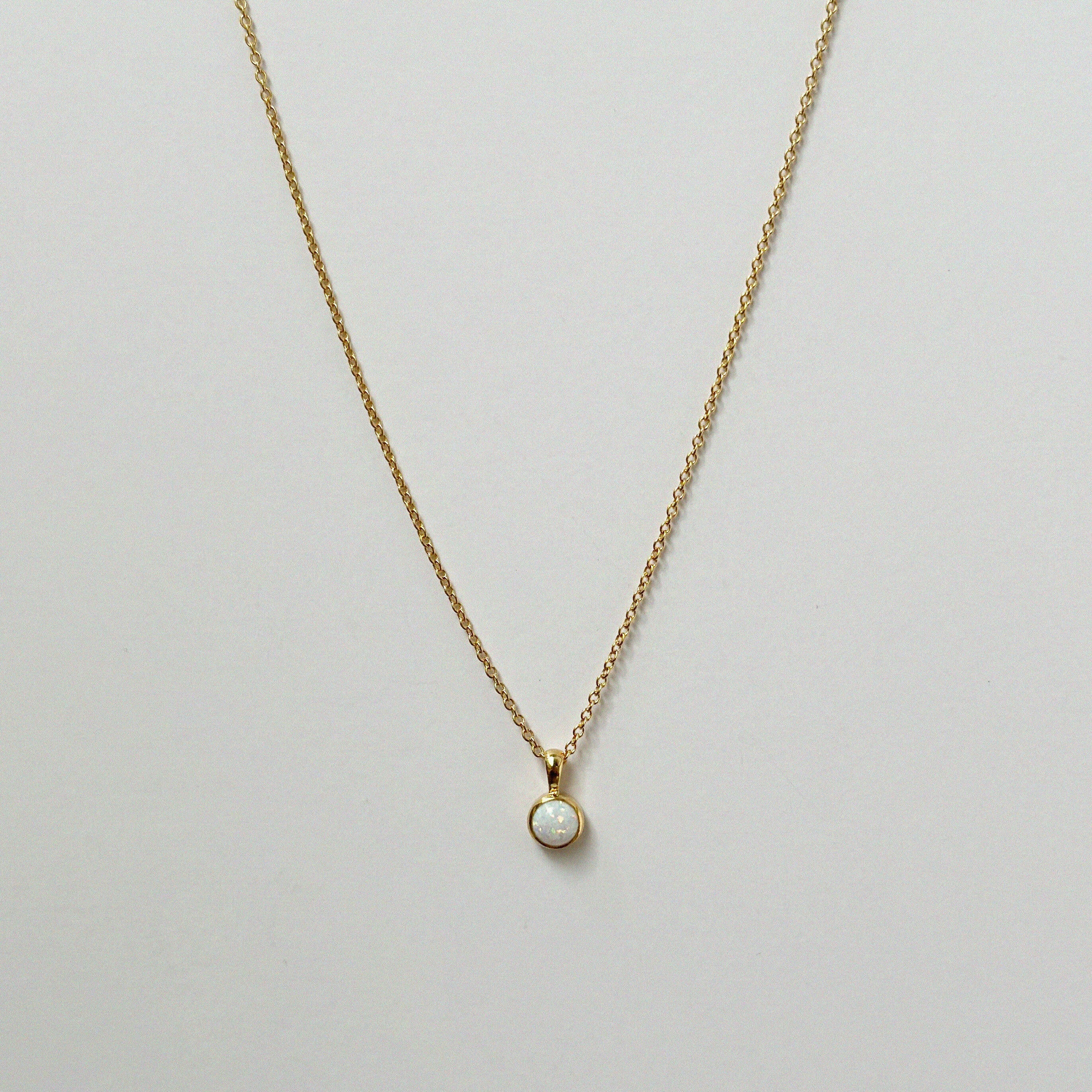 Delicate circular white opal necklaces arranged in a minimal flat lay