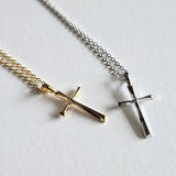 Close-up of Gold and silver cross necklaces displayed side by side with minimalist cross design