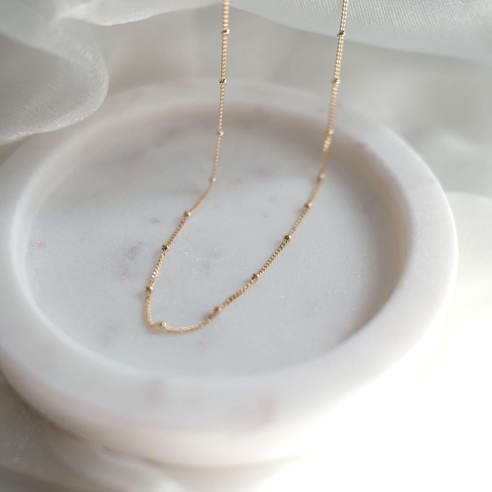 Gold necklace on a white marble surface