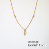 Gold filled necklace with leaf pendant and moonstone beads laid flat
