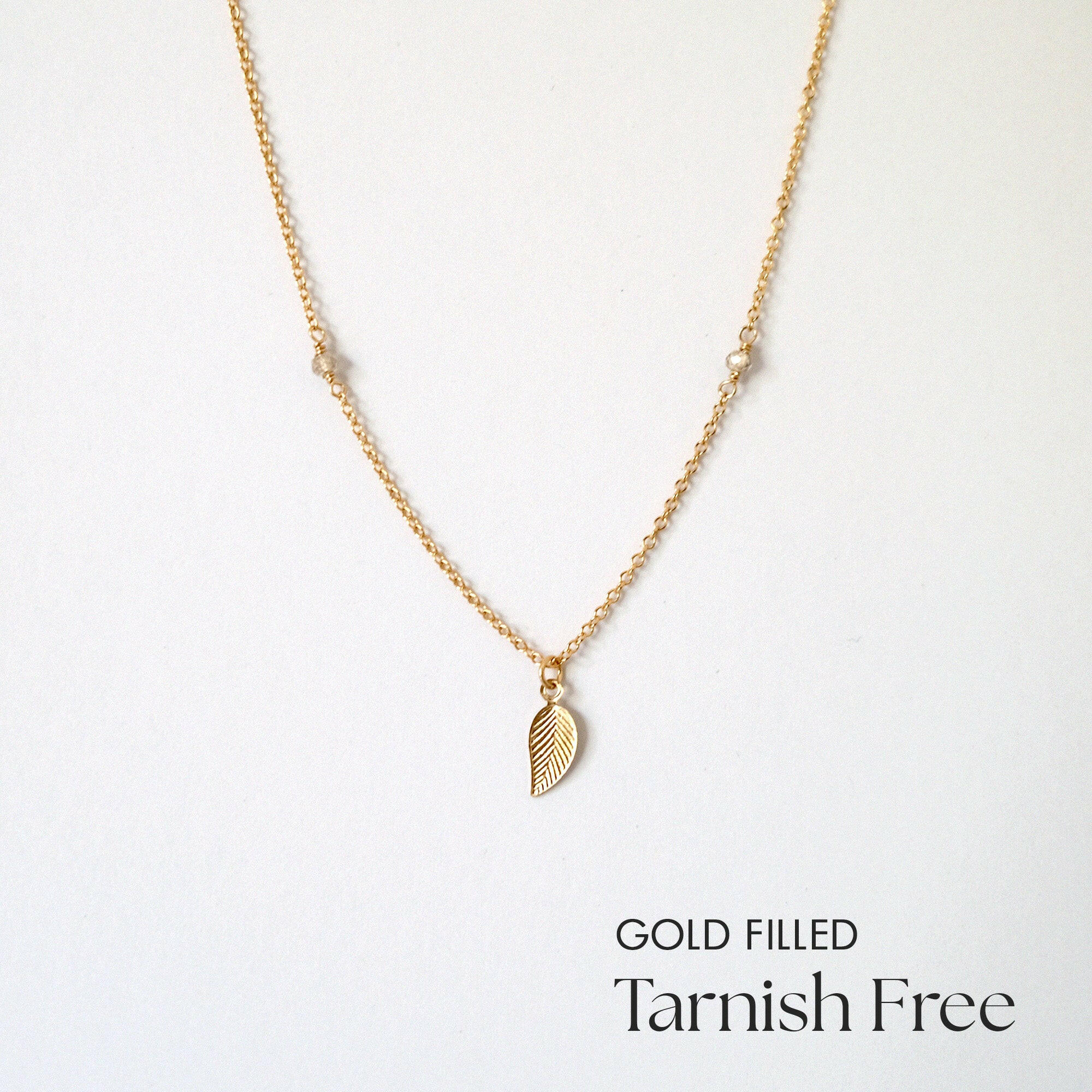 Gold filled necklace with leaf pendant and moonstone beads laid flat