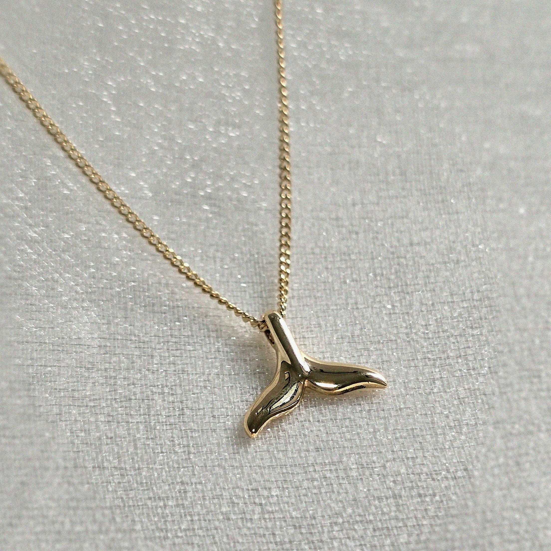 Overhead view of whale tail charm on fine chain – highlighting craftsmanship